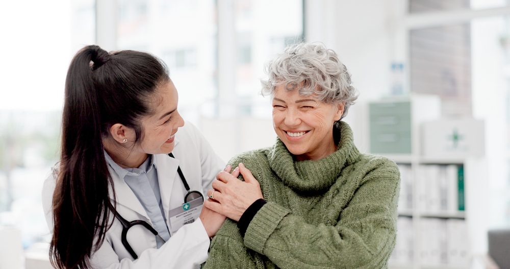 female doctor comforting elderly woman with green sweater